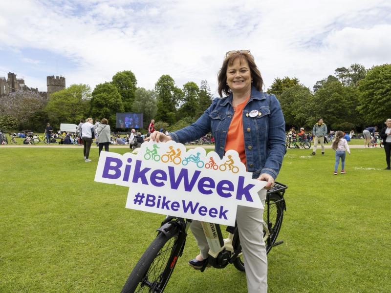 Woman on bike holding bike week promotional signage