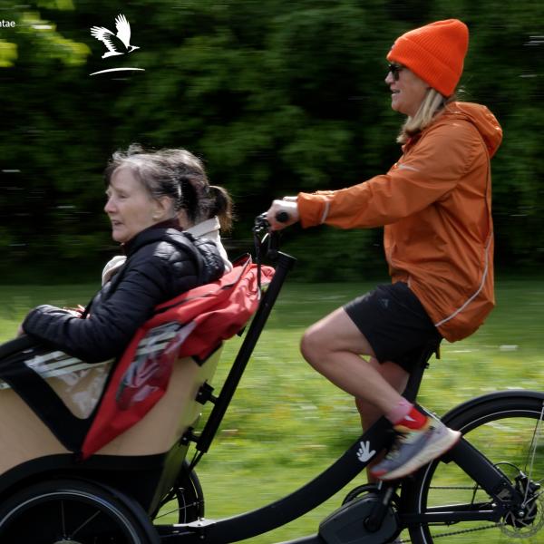 Woman in orange hat cycling trishaw