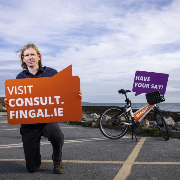 Man kneels with sign in hands saying consult.fingal.ie