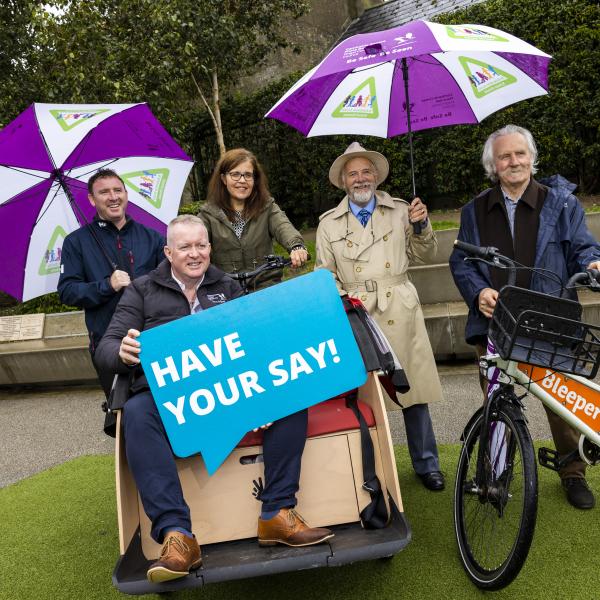 Man sitting on cargo bike and people with umbrellas