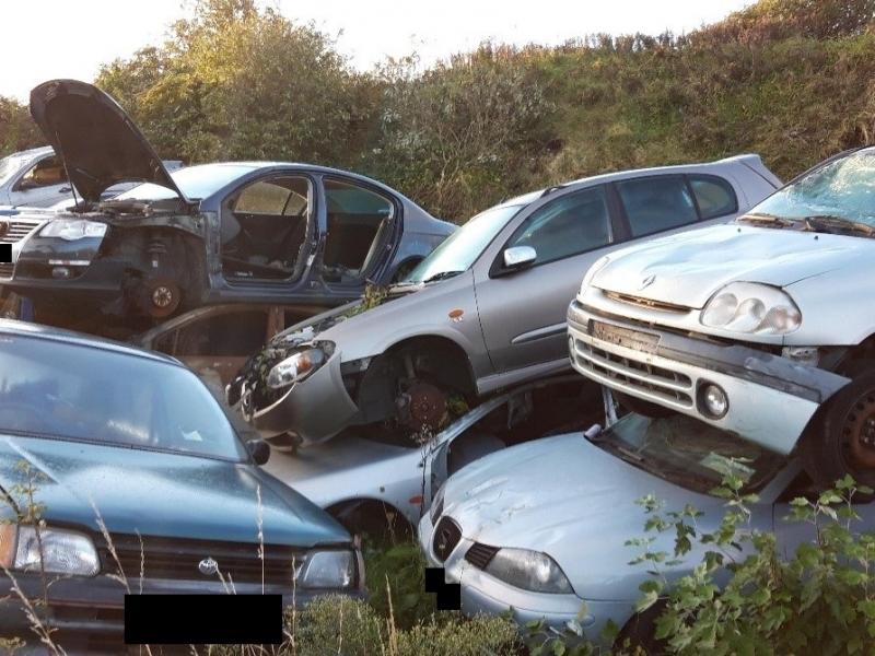 Further end of life vehicles piled on one another in a ditch