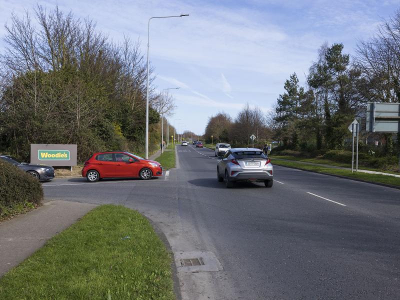 Cars travelling on road as red car joins at junction on left