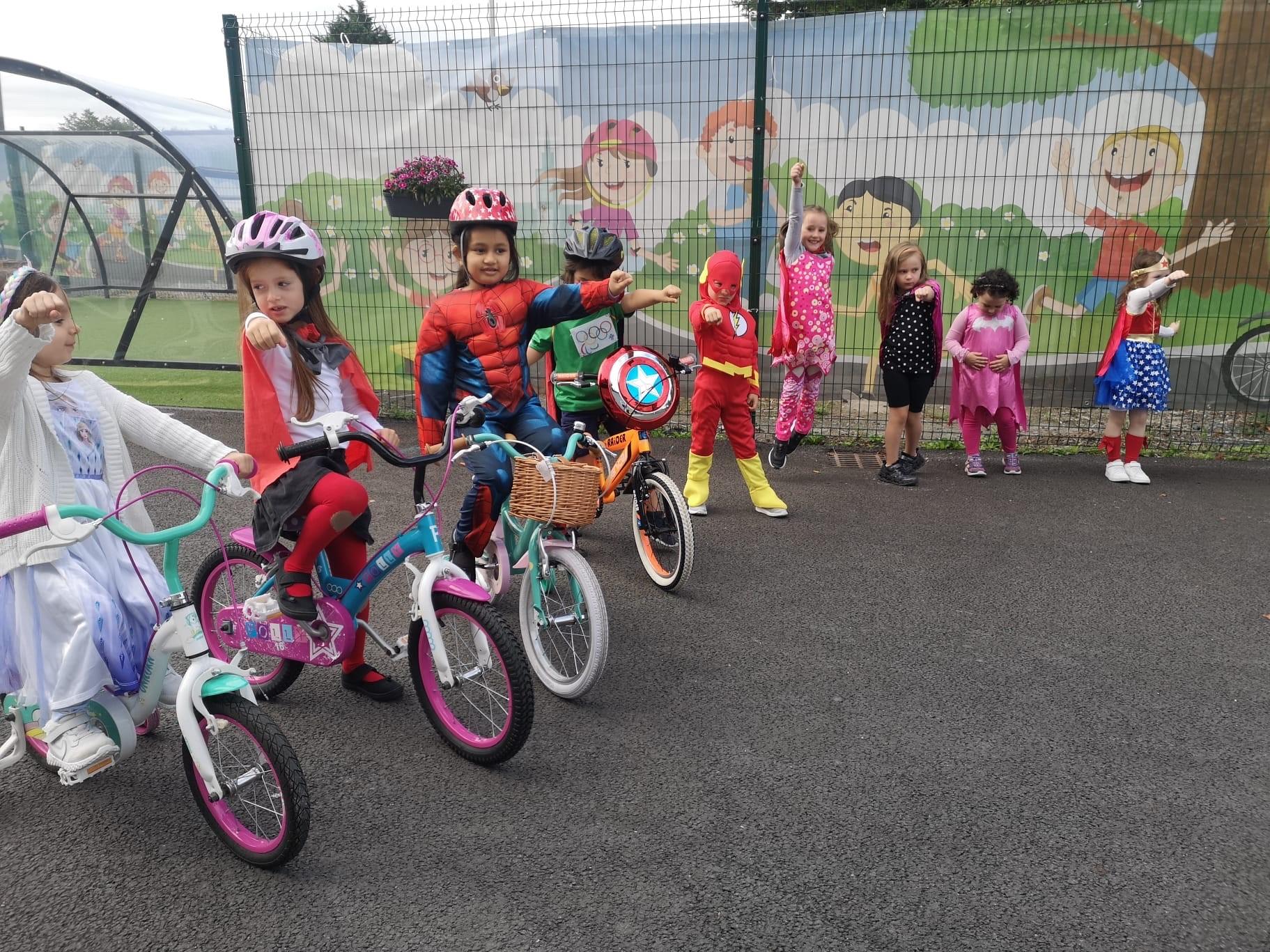 Children on bikes wearing superhero costumes