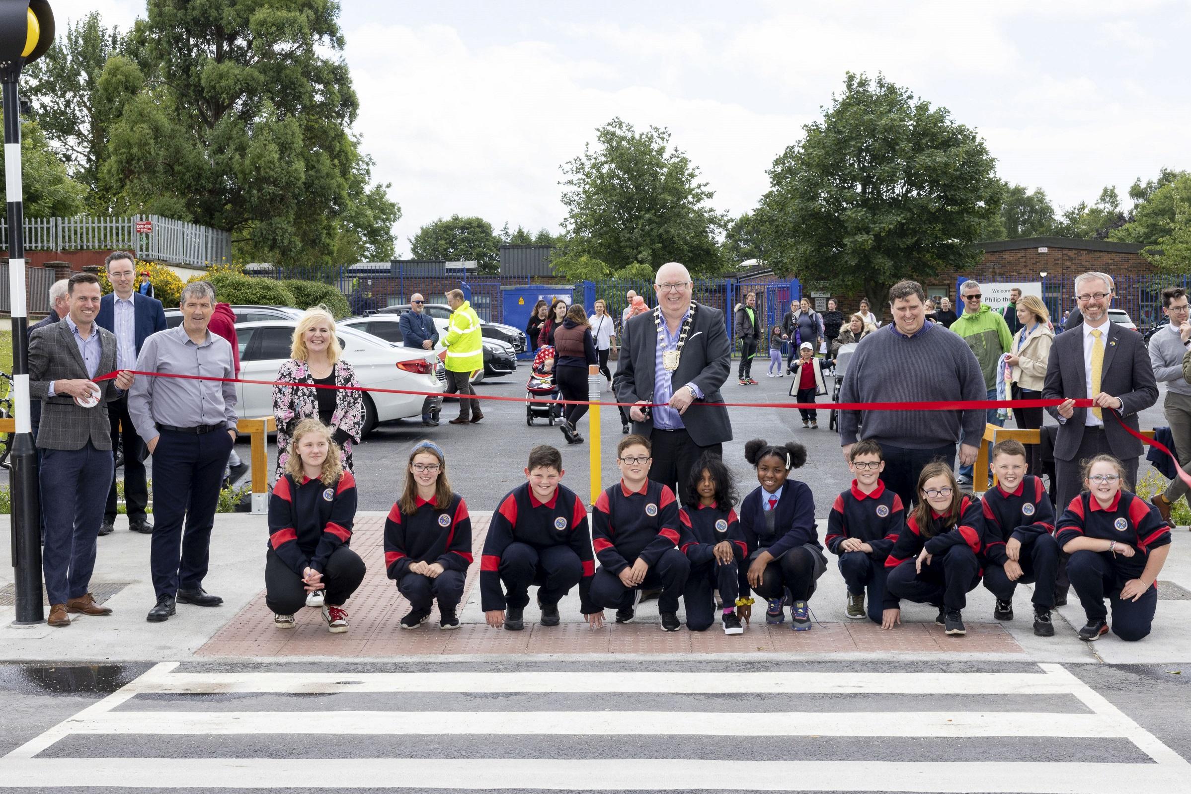 children and adults at zebra crossing with ribbon cutting