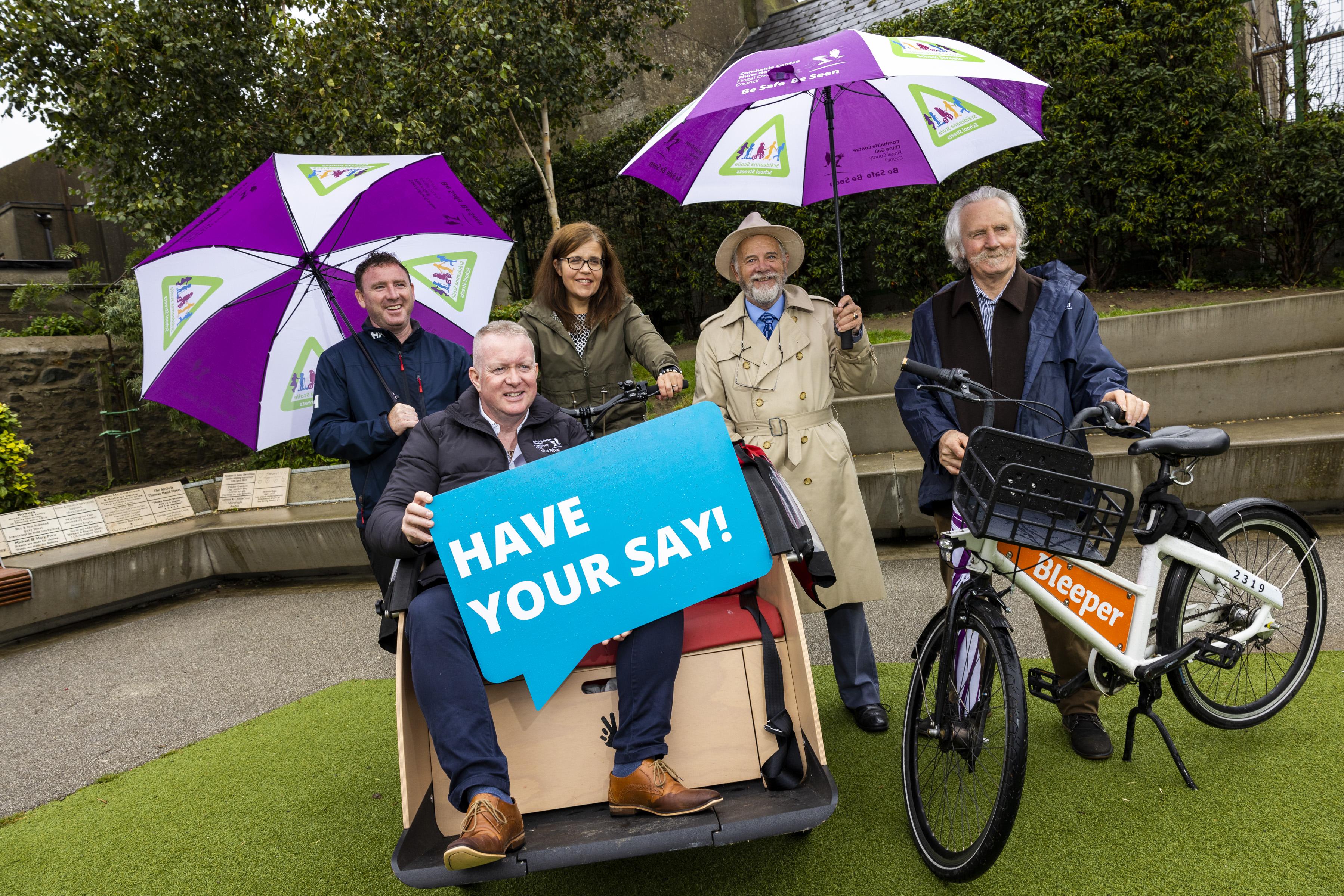 Man sitting on cargo bike and people with umbrellas