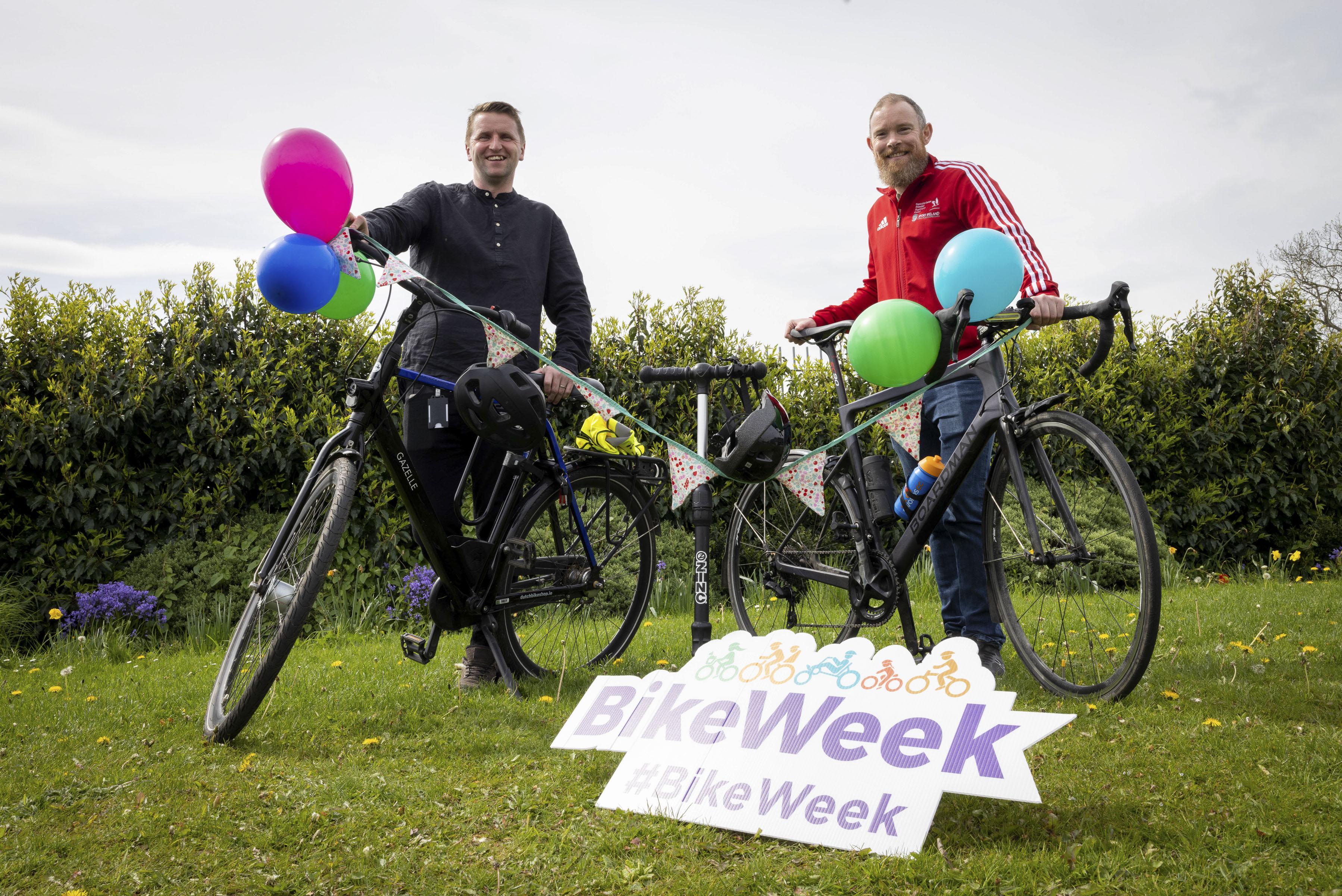 Two people standing with bikes and bike week sign